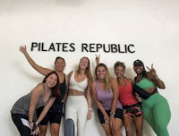 a group of women posing in front of a pilates republic sign