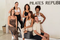 a group of people posing in front of a pilates republic sign