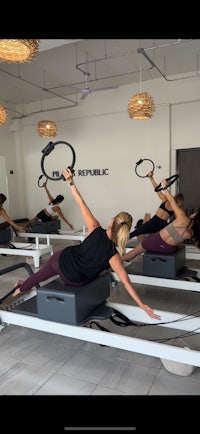 Women doing Reformer Pilates oblique work with pilates ring
