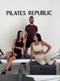 three people posing in front of a pilates republic sign