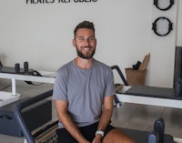 a man sitting on a pilates mat in a gym