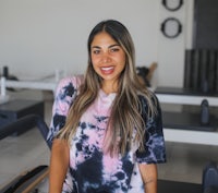 a woman in a tie dye t - shirt sitting on a pilates mat