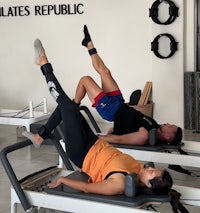 Man and woman doing pilates reformer bridge
